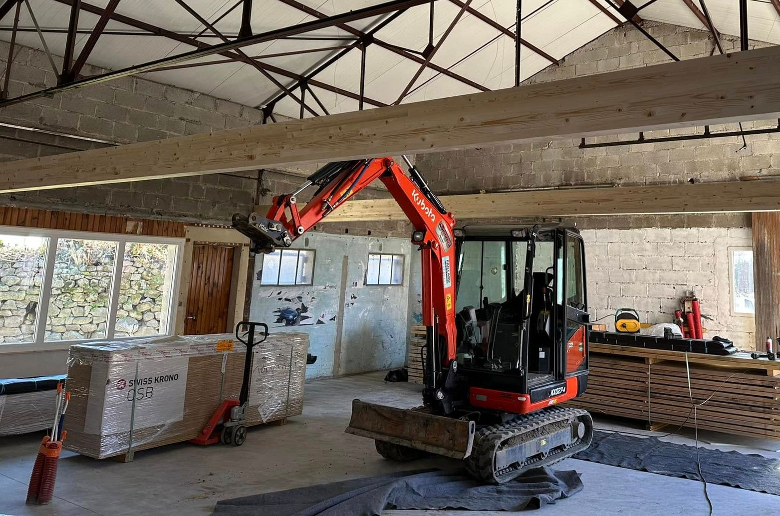 Minipelle à l'intérieur d'un bâtiment avec de grandes poutres en bois et des fenêtres.