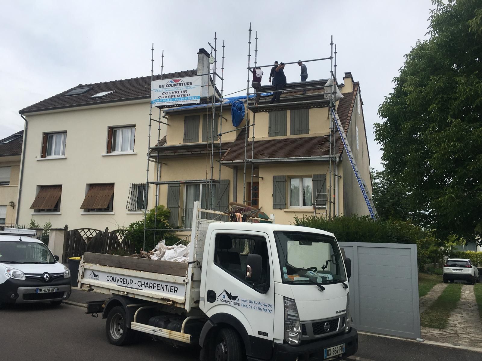 Camionnette de travaux en premier plan et les travaux de couverture en cours.