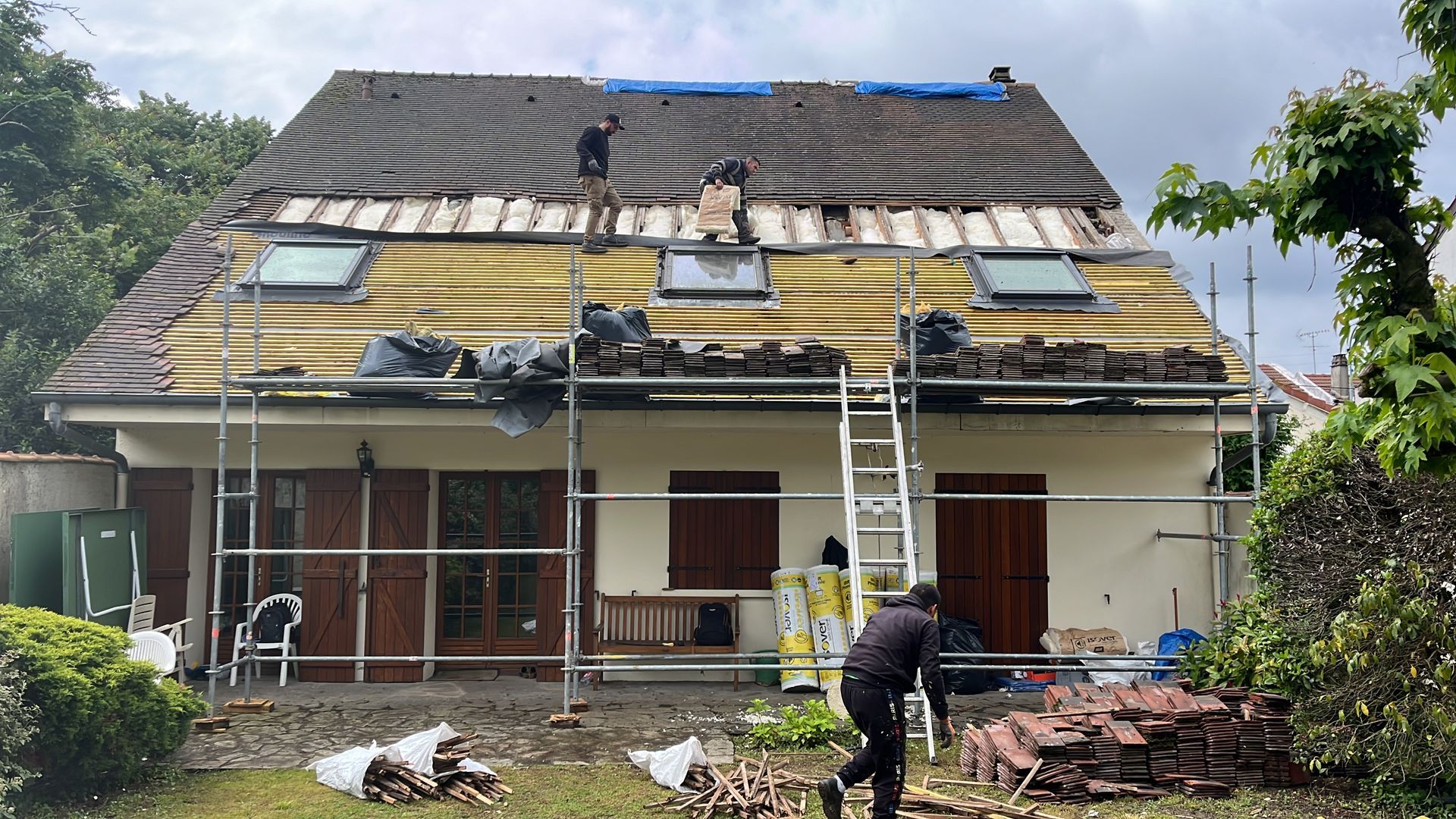 Des personnes en train de poser un isolant sur la toiture en ardoise.