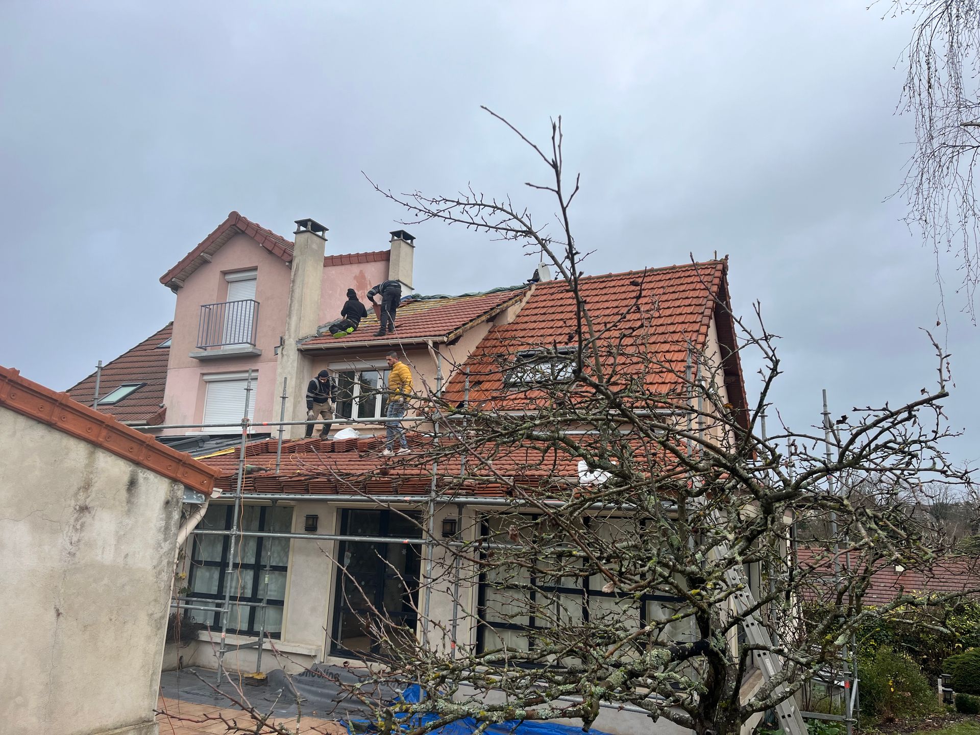 Maison avec deux couvreurs sur le toit en tuile.