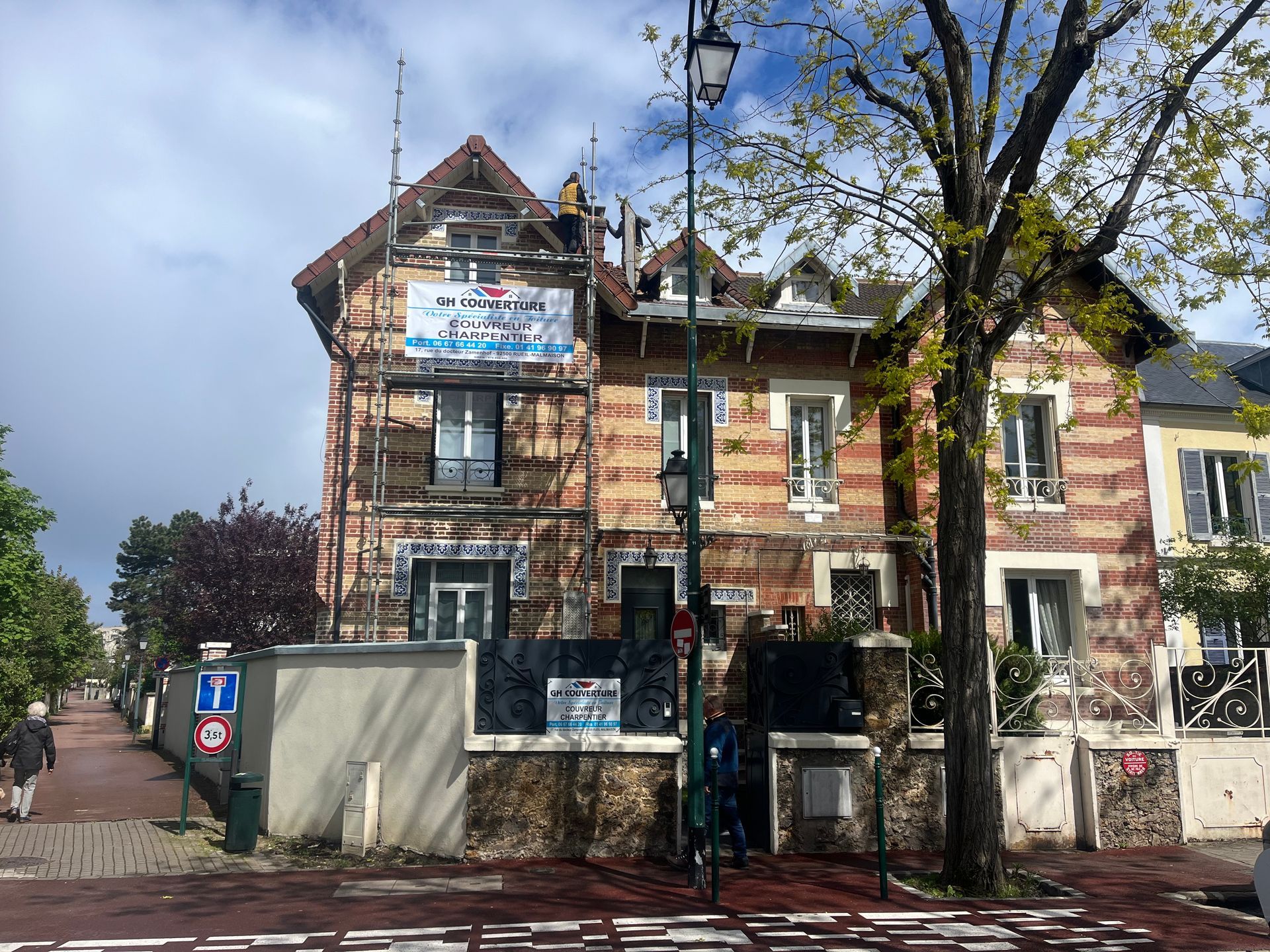 Maison en brique avec un échafaudage devant et une affiche.