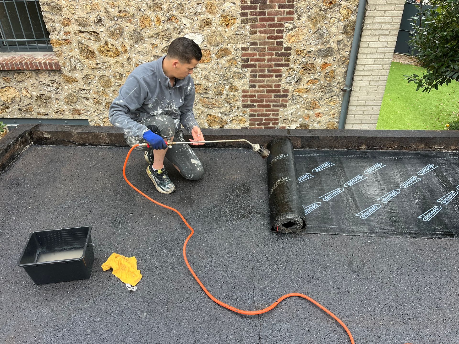 Un professionnel en train de refaire l'étanchéité d'un toit plat.