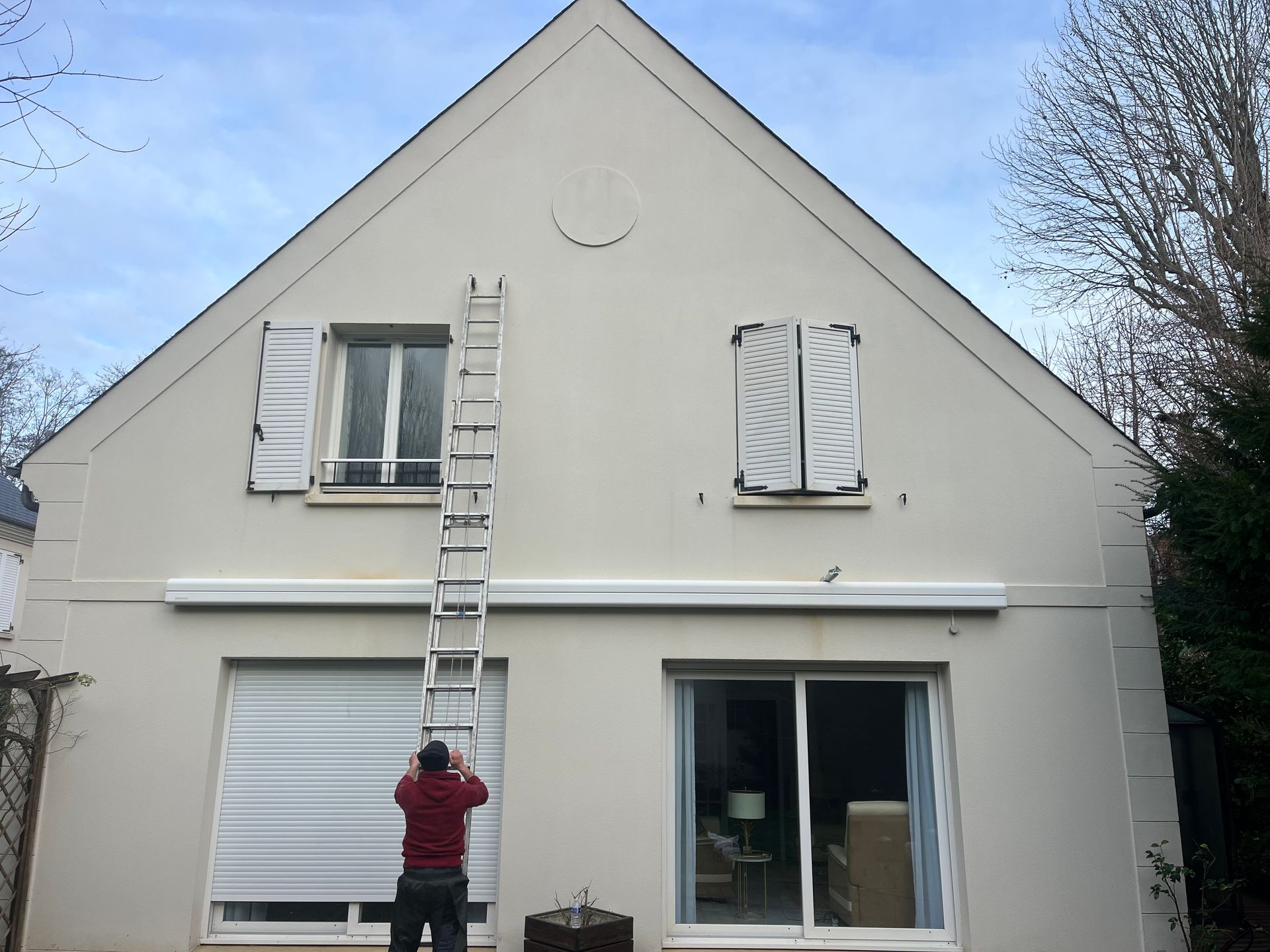 Une personne avec l'échelle contre le mur d'une maison.