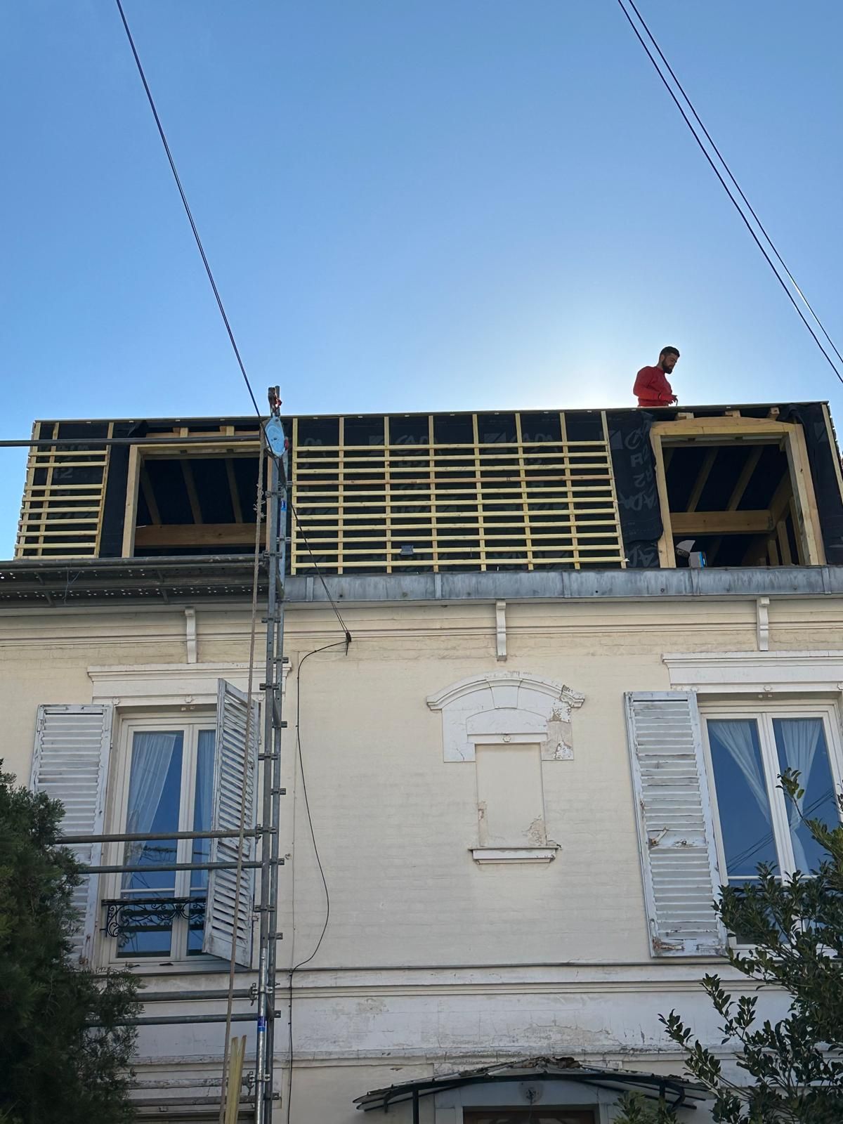 Une personne en train de remettre les ardoises sur une toiture en travaux.