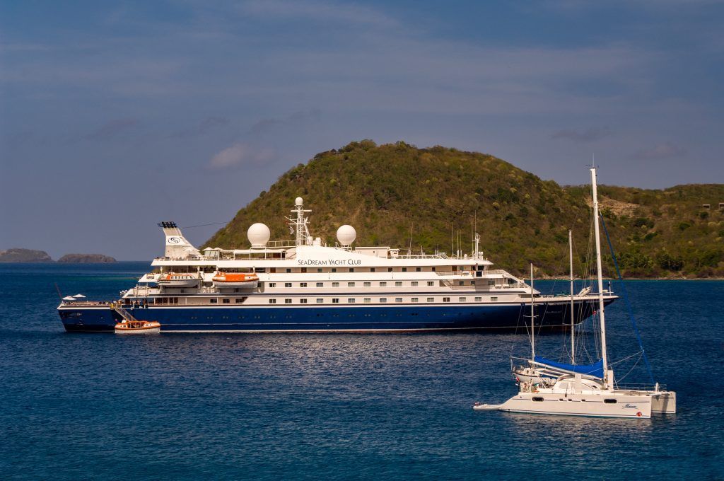 City skyline along a lake at sunset with a tall church steeple, under a vibrant, colorful sky.