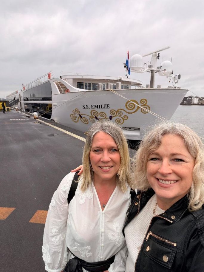 City skyline along a lake at sunset with a tall church steeple, under a vibrant, colorful sky.