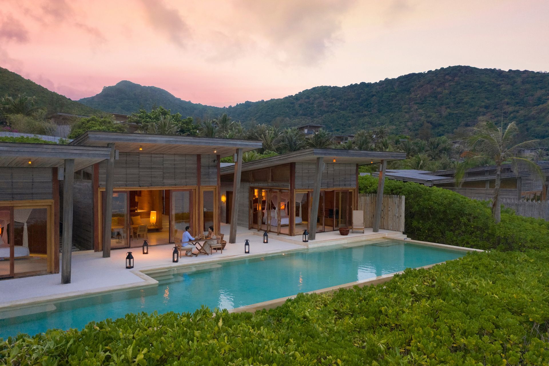 Luxury villa with turquoise pool and mountains at sunset.
