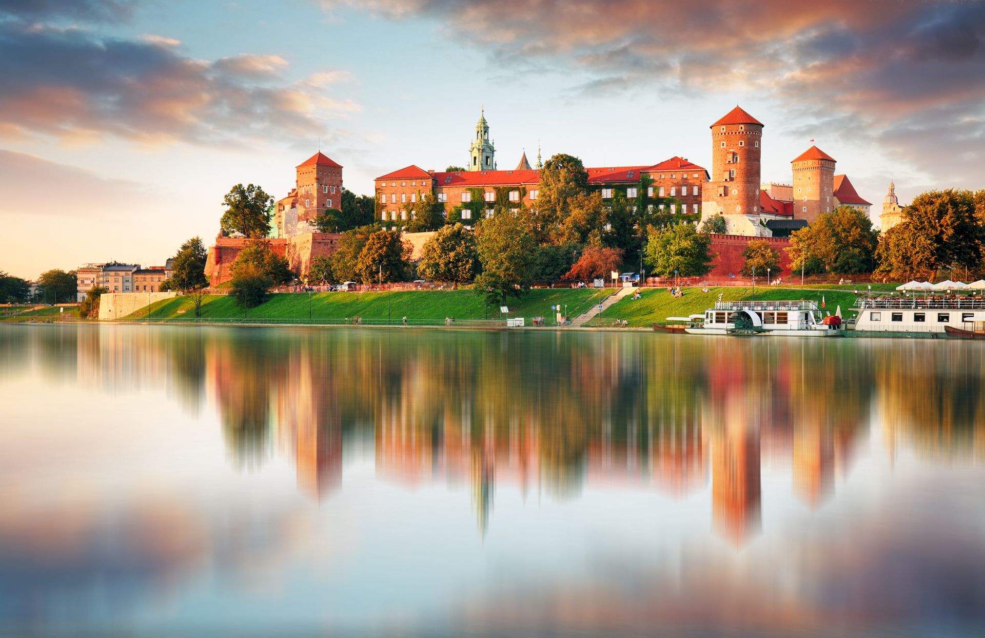 Wawel Castle in Krakow, Poland, reflected in the Vistula River at sunset.