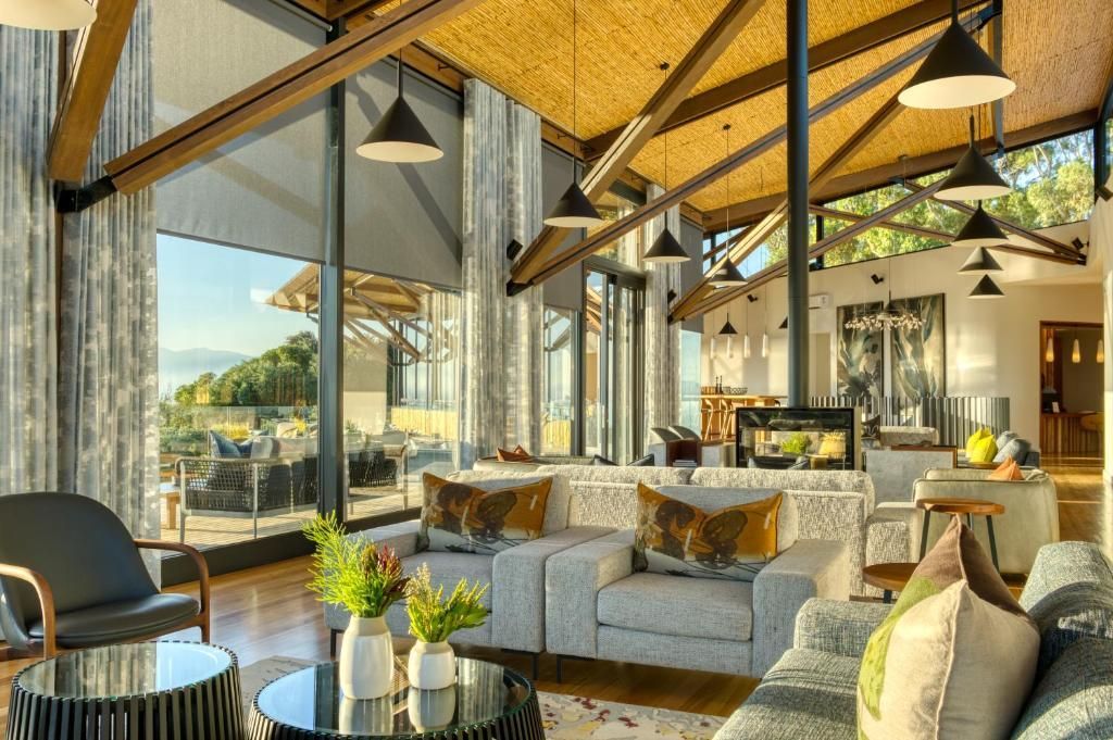 Lounge area with large windows, sofas, fireplace, and lamps, overlooking a scenic view.