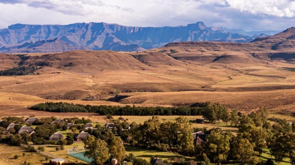 Rolling hills with a village and mountains in the background, likely in South Africa.