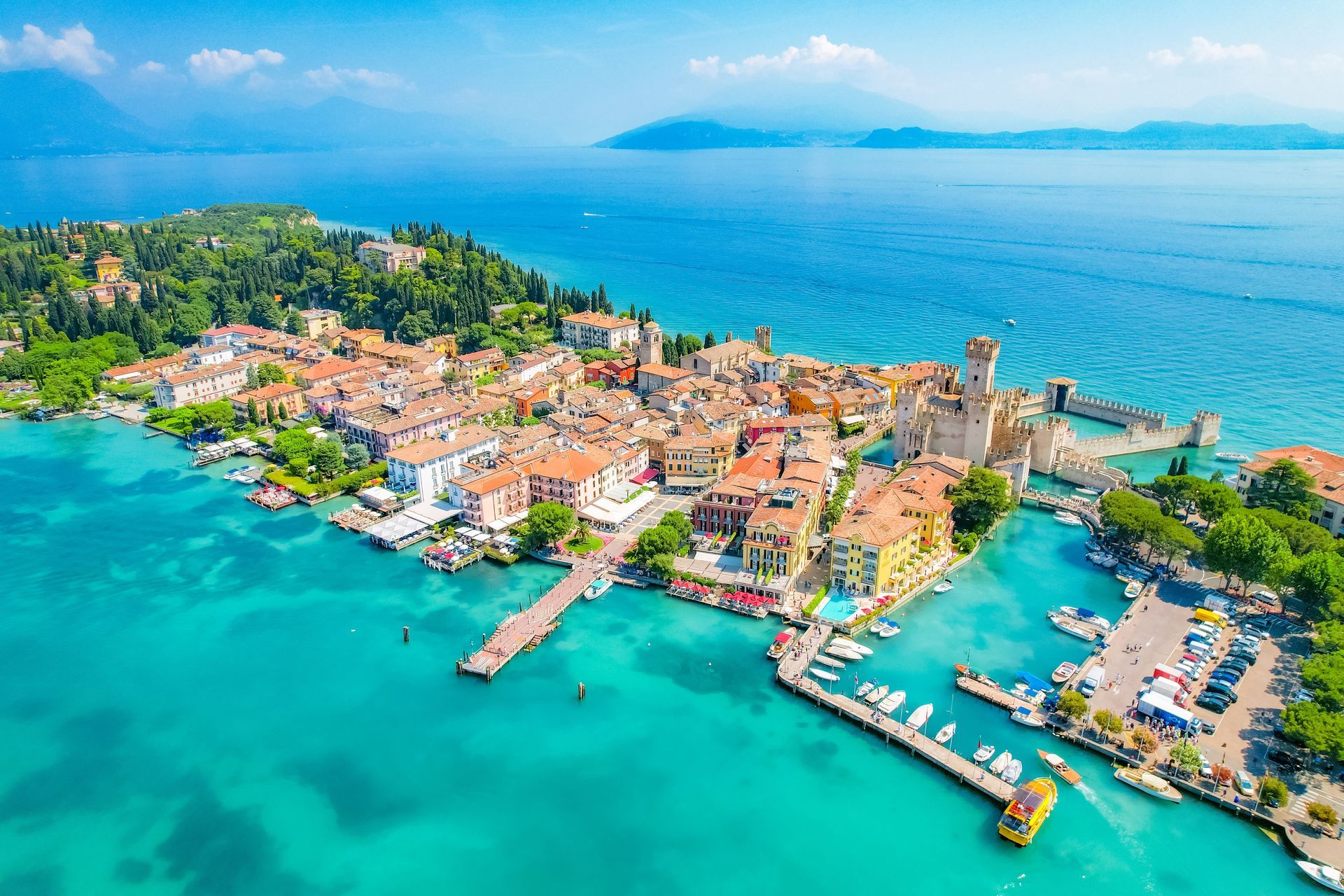 Aerial view of Sirmione, Italy on Lake Garda, with turquoise water, colorful buildings, and a castle.