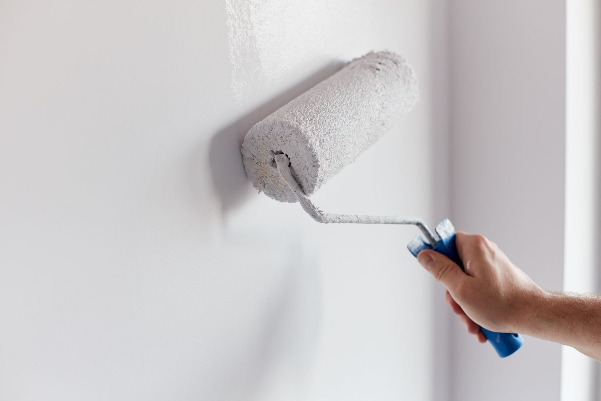 Un rouleau à peinture sur un mur intérieur blanc