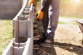 Ouvrier posant des blocs de béton sur un mur de construction à l'extérieur