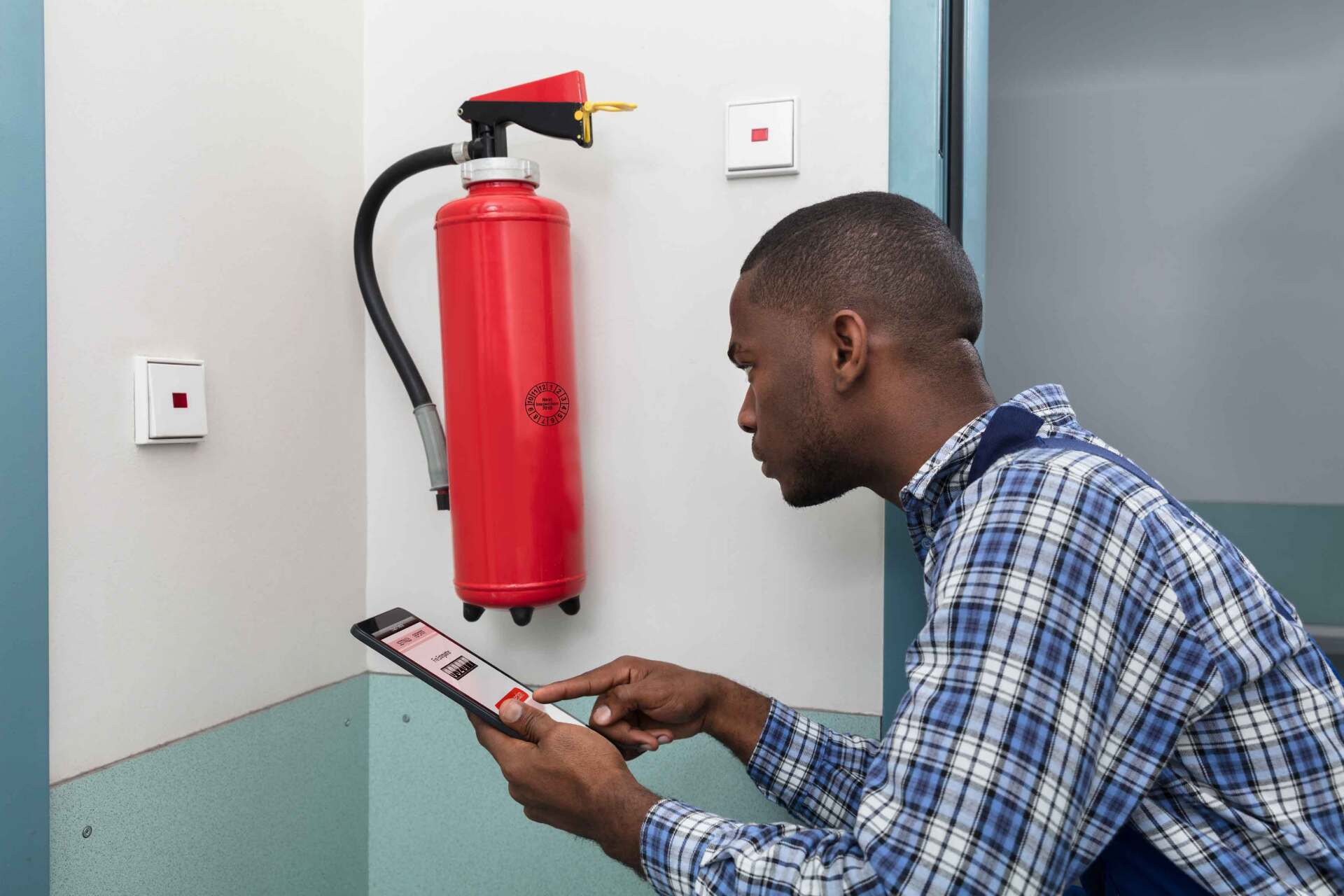 Homme qui regarde une tablette avec un extincteur à côté