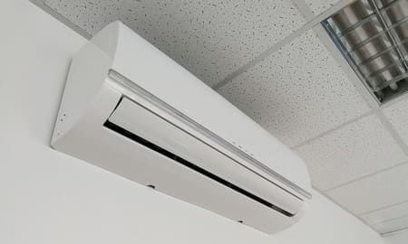 Un acondicionador de aire blanco está colgado en una pared blanca.