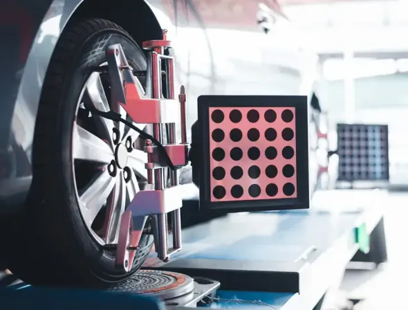 Rueda de automóvil durante una verificación de alineación en un taller, utilizando un equipo de diagnóstico.