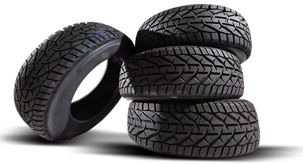 Cuatro neumáticos negros apilados, uno apoyado contra la pila.