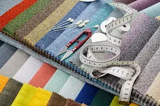 Muestras de tela en varios colores con tijeras, cinta métrica y alfileres.