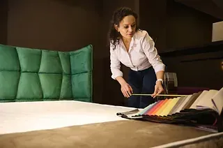 Mujer seleccionando muestras de tela para una cabecera de mechones verdes en una sala de exposición.