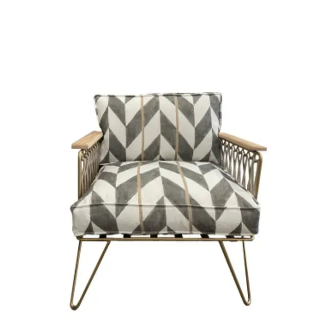 Sillón estampado en gris y blanco con estructura dorada y reposabrazos de madera.