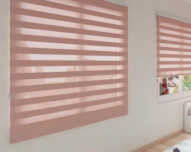 Dos ventanas con persianas de cebra de color rosa claro sobre una pared blanca.