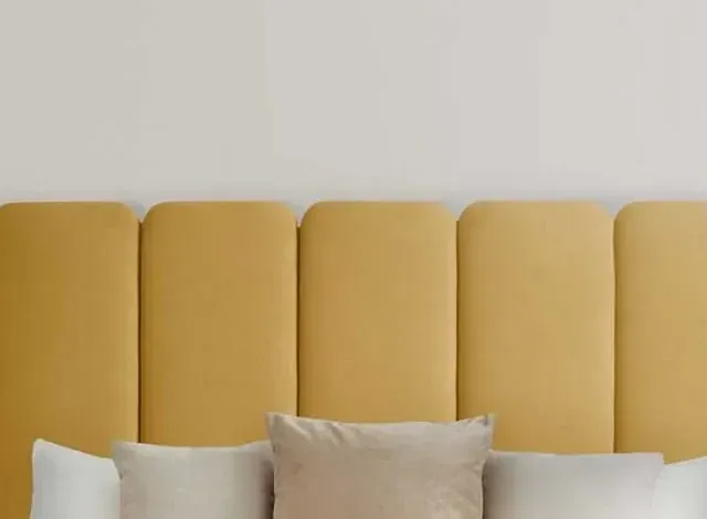 Cabecero tapizado en color amarillo con almohadas.