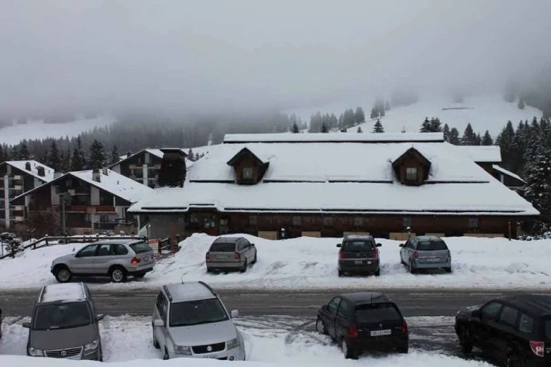 Des voitures sont garées devant un bâtiment recouvert de neige