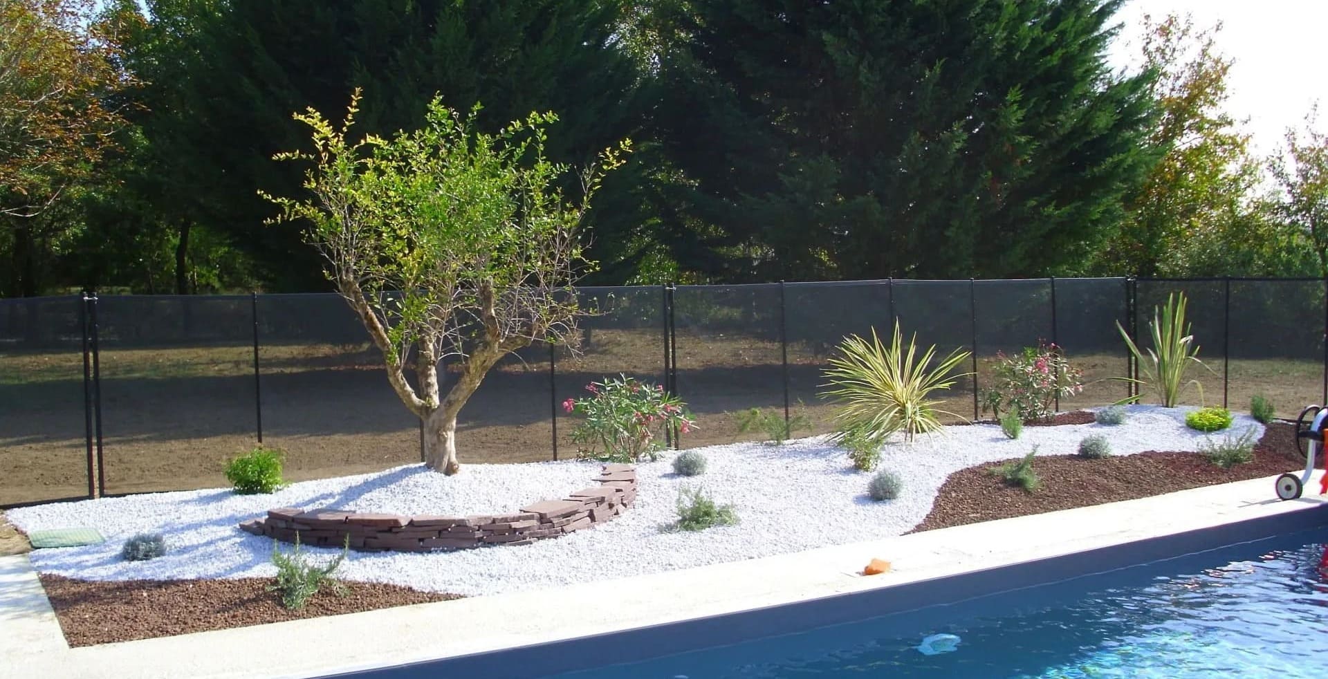 Bordure de piscine avec arbustes et gravillons