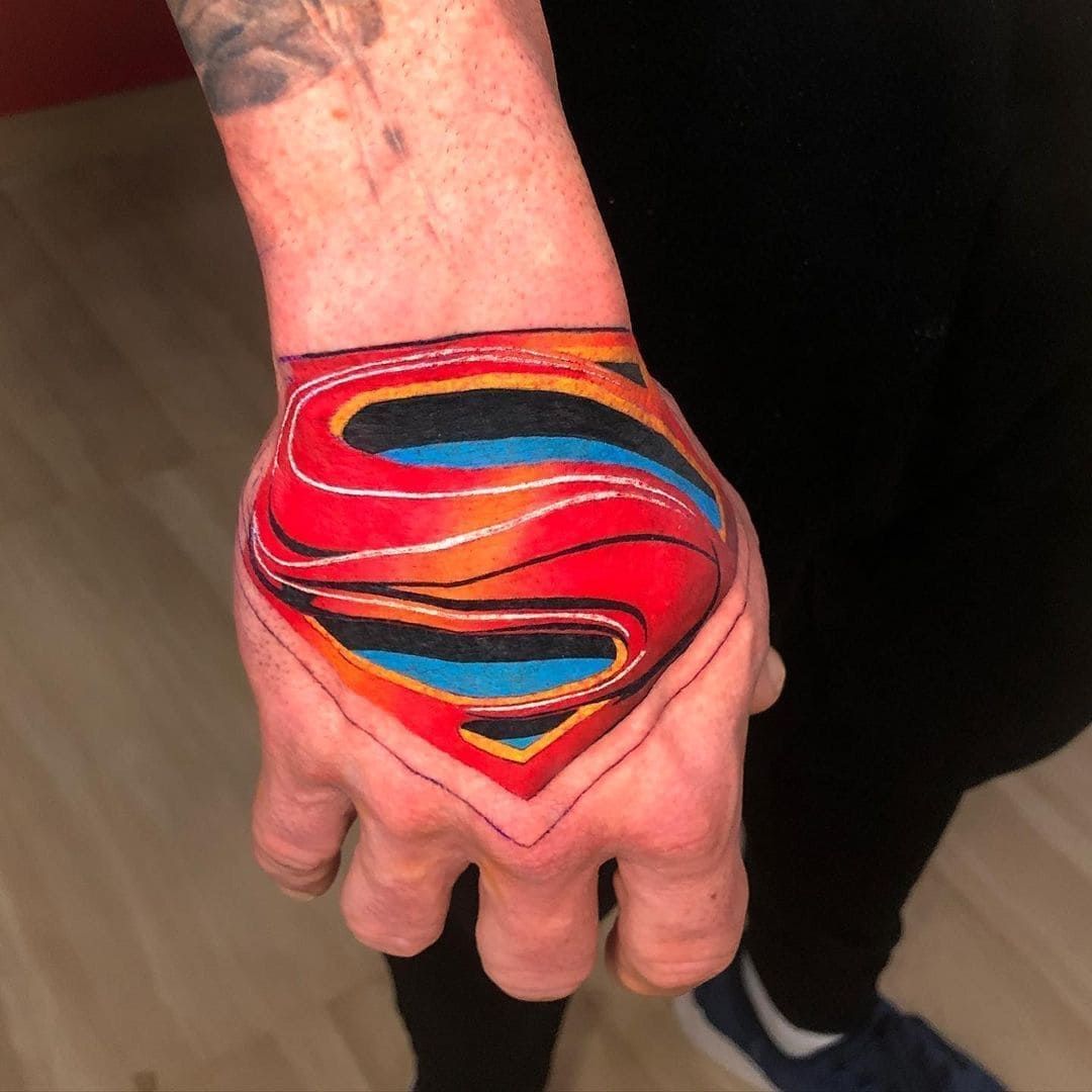 Mano con el colorido logo de Superman pintado en la parte posterior.