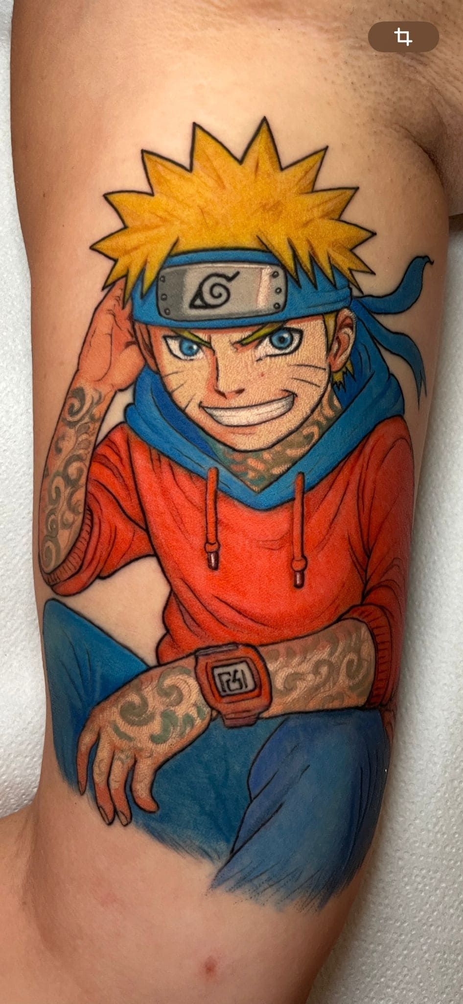 Tatuaje colorido de Naruto en un costado del torso, que muestra al personaje con una chaqueta naranja y una diadema azul.