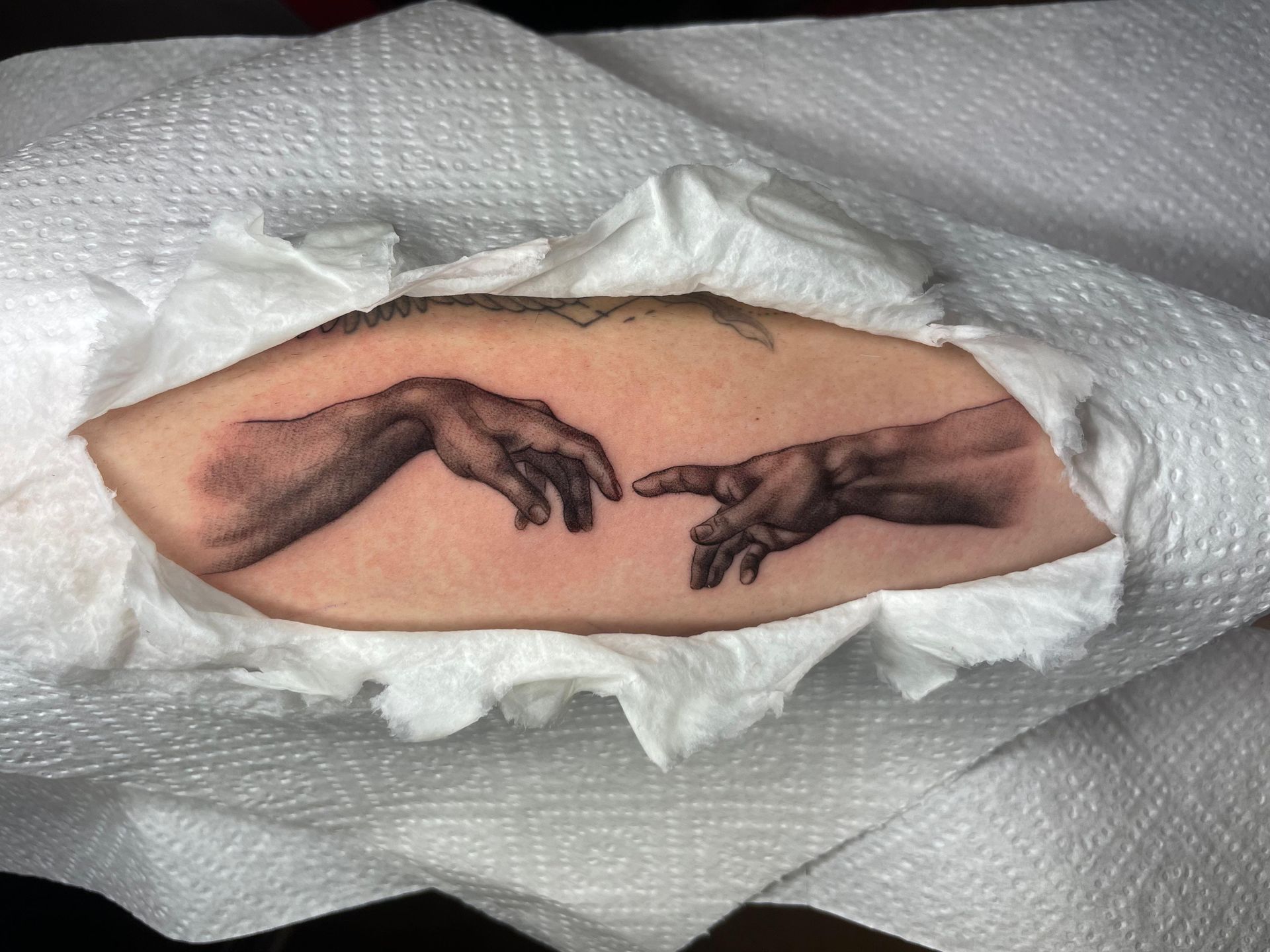 Dos manos extendidas tatuadas en la piel, rodeadas de gasa o tejido blanco.