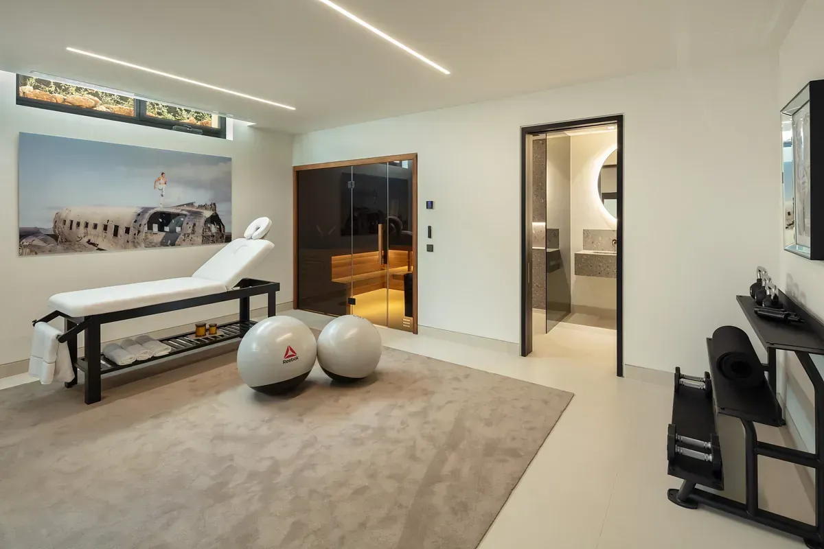 Sala de spa con mesa de masajes, pelotas de ejercicio, sauna y acceso al baño.