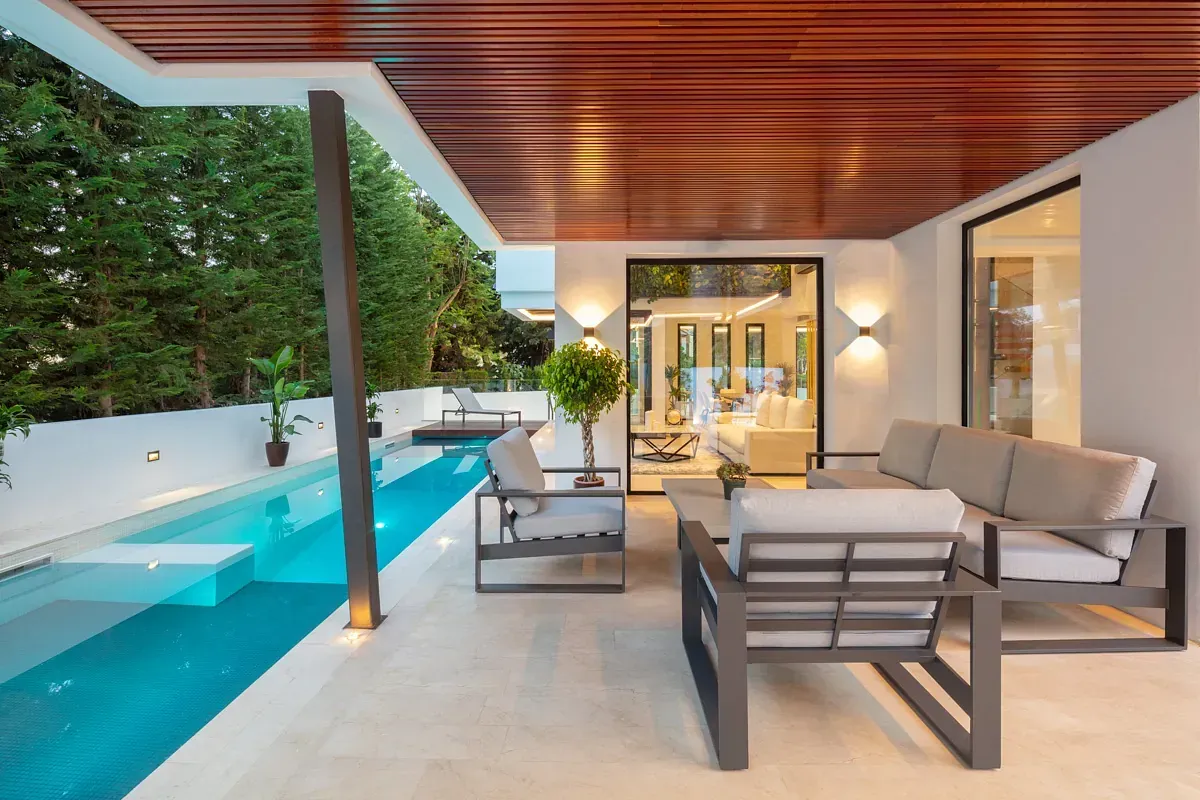 Patio con muebles modernos, piscina y techo de madera.