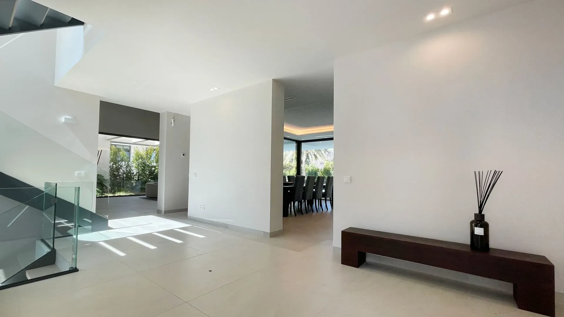 Interior de casa moderna con paredes blancas, banco de madera y escalera.