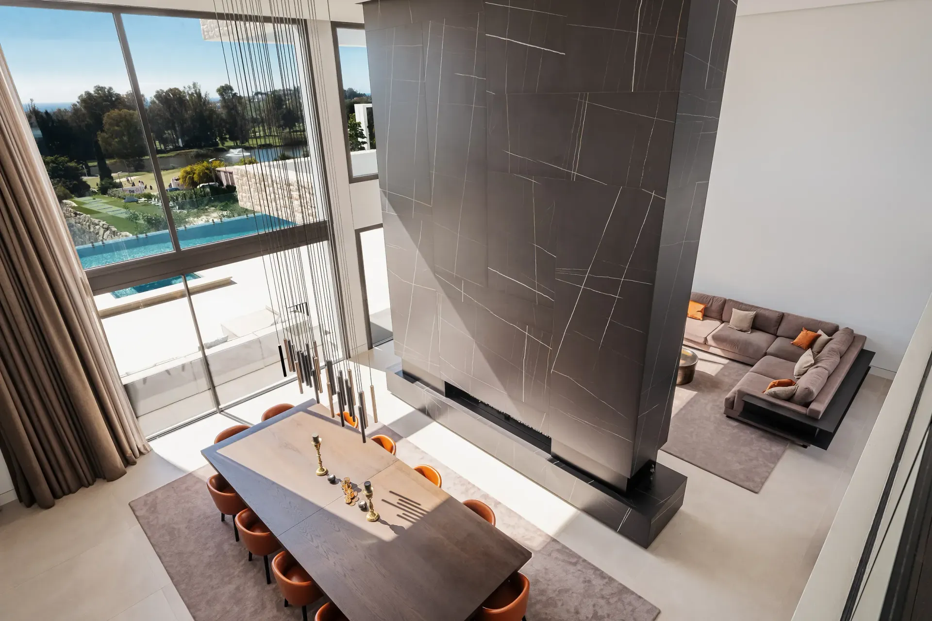 Vista en ángulo alto de un moderno comedor, sala de estar y patio, con ventanas altas.