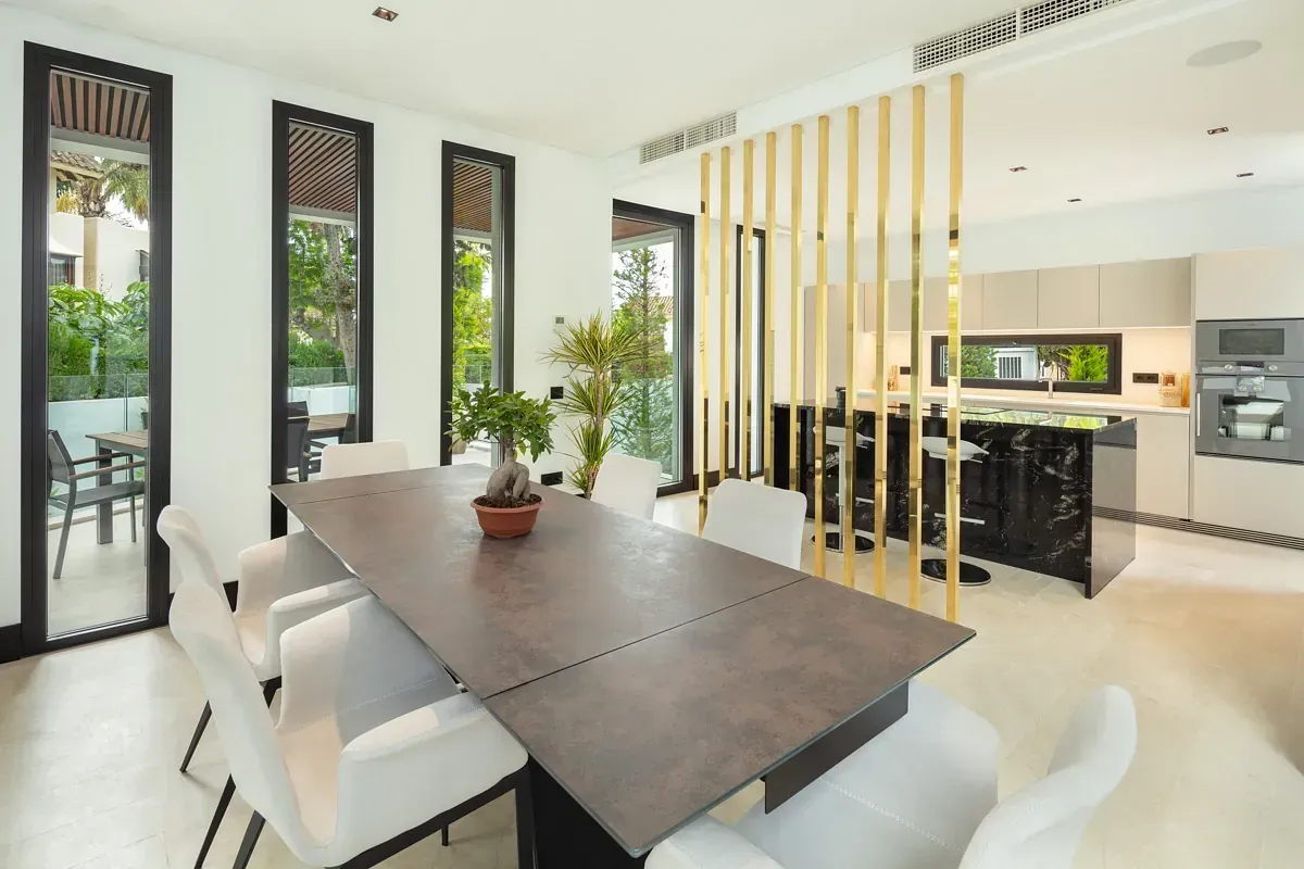 Comedor con mesa grande, abierto a la cocina y puertas corredizas a un patio.