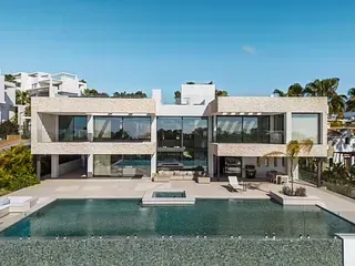 Villa moderna con piscina infinita, cielo azul y exterior soleado, con paredes de vidrio y asientos de lujo al aire libre.