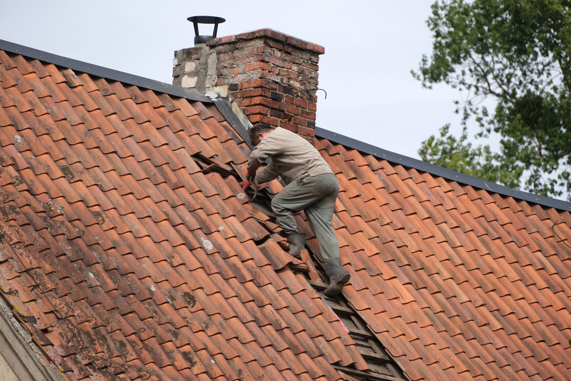 Homme descendant d'une toiture en tuiles rouges