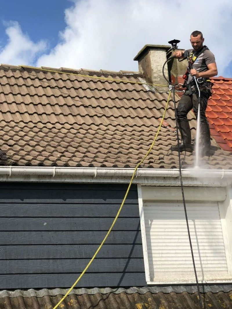 Intervention sur une toiture en tuiles avec utilisation d’un nettoyeur haute pression.
