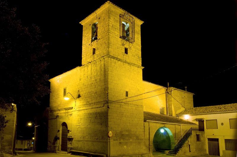 Un gran edificio con una torre de reloj se ilumina por la noche.
