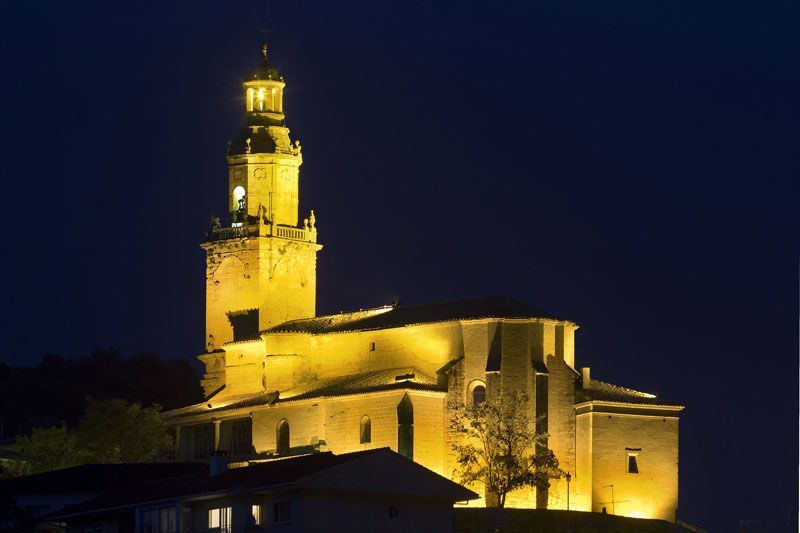 Un gran edificio con una torre de reloj está iluminado por la noche.