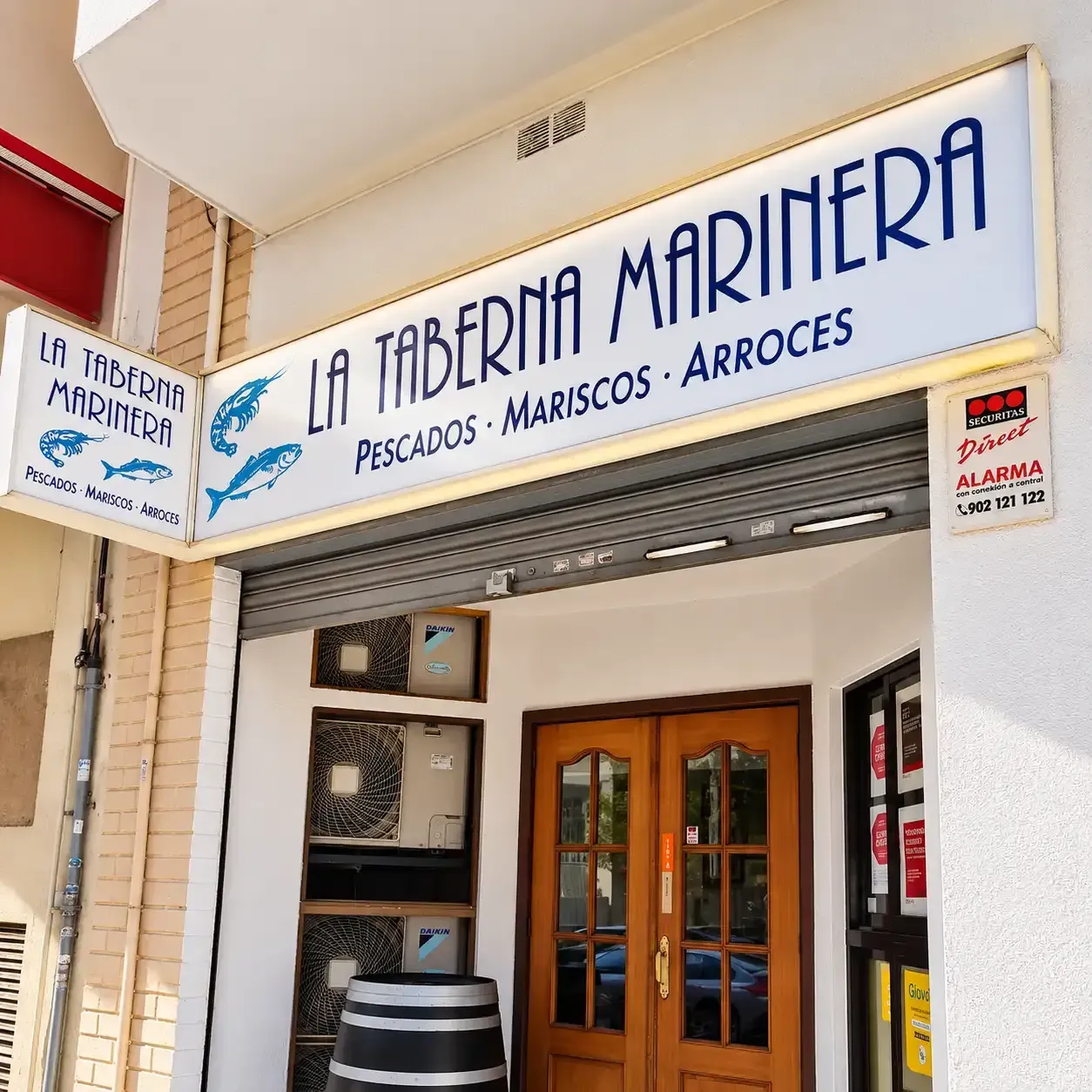 Entrada al restaurante de mariscos y arroz La Taberna Marijera con letrero azul y puertas de madera.