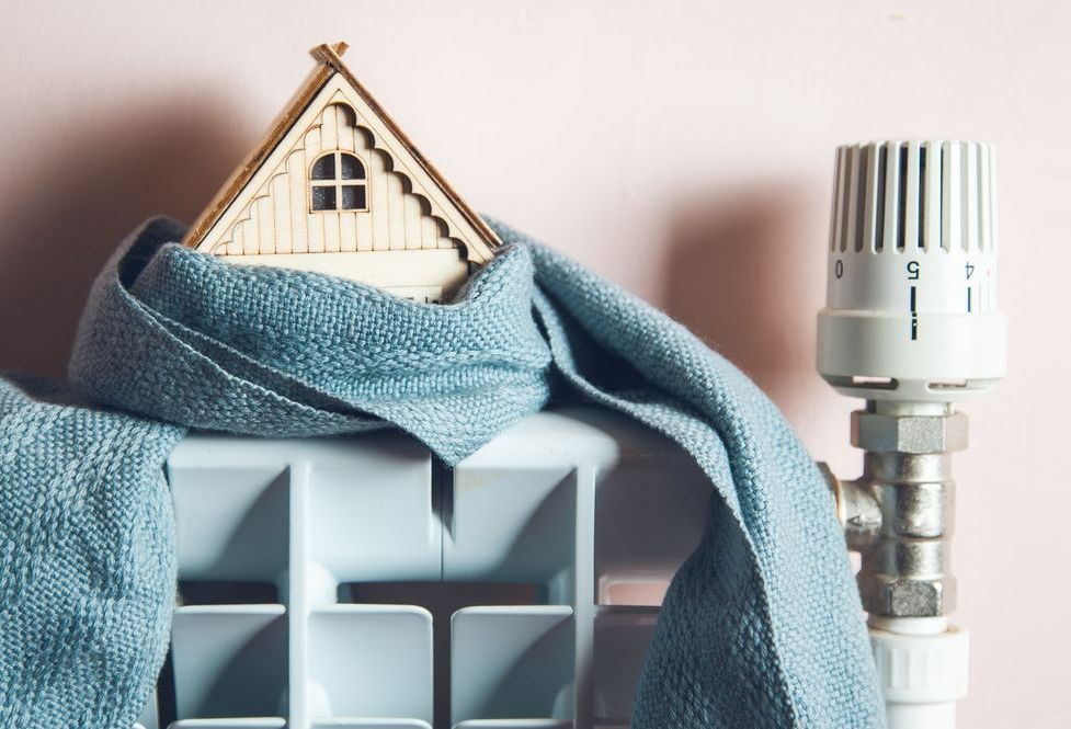Une petite maison en bois enroulée dans une écharpe posée sur un chauffage