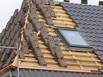 Toiture en construction avec tuiles brunes et puits de lumière.