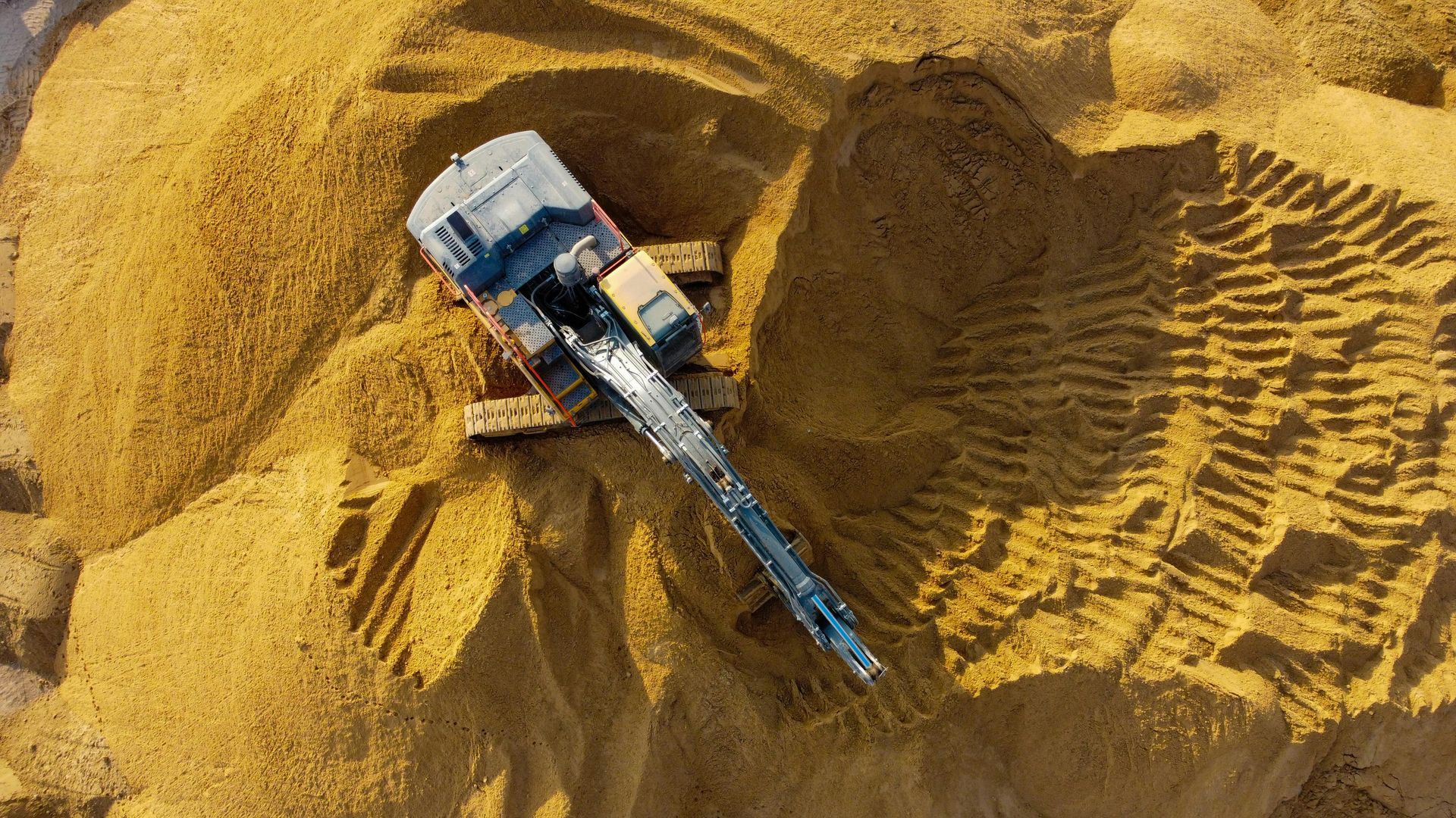 Eine Luftaufnahme eines Bulldozers, der einen Sandhaufen bearbeitet.
