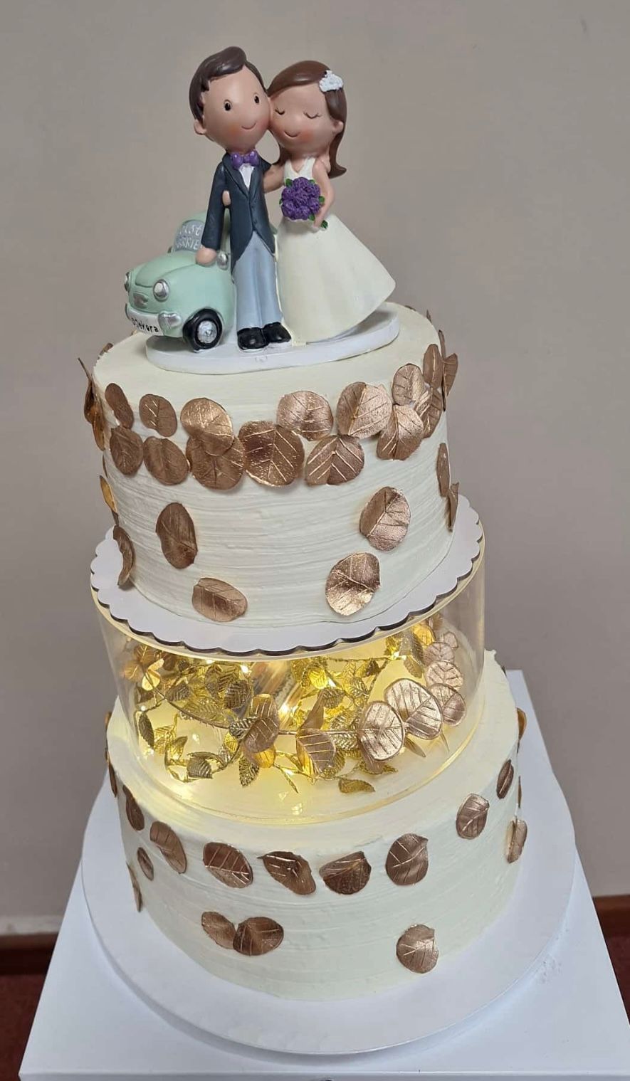 Un pastel de bodas con una figura de novios encima.