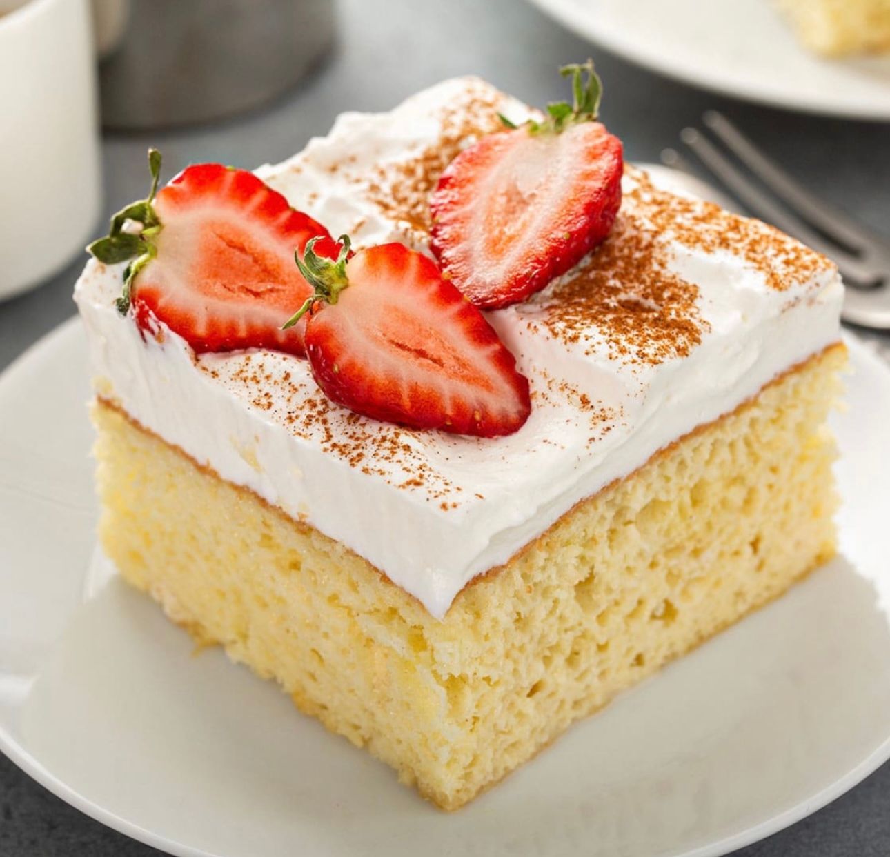Un trozo de pastel con crema batida y fresas encima.