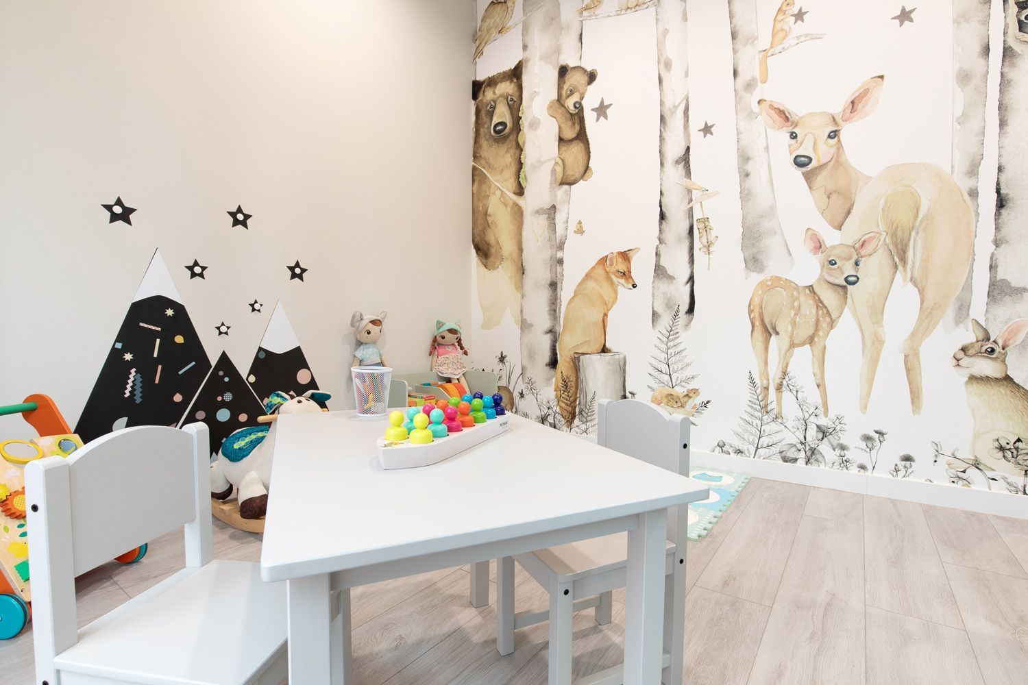 Una habitación infantil con un mural de animales en la pared.