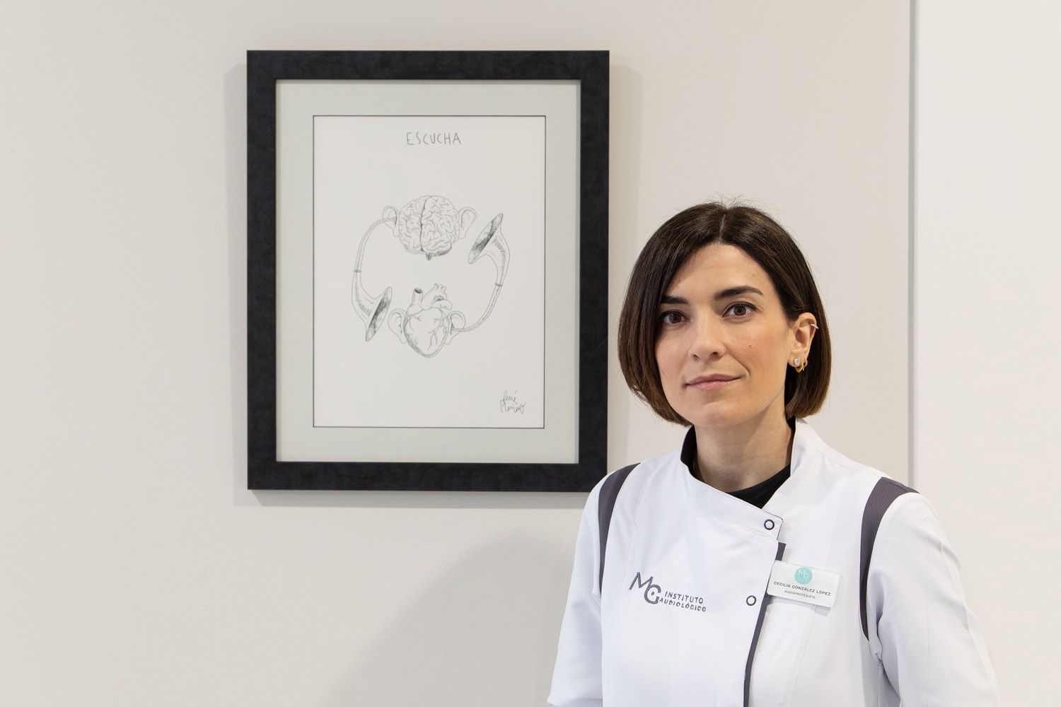 Una mujer está sentada en una mesa frente a un cuadro en la pared.