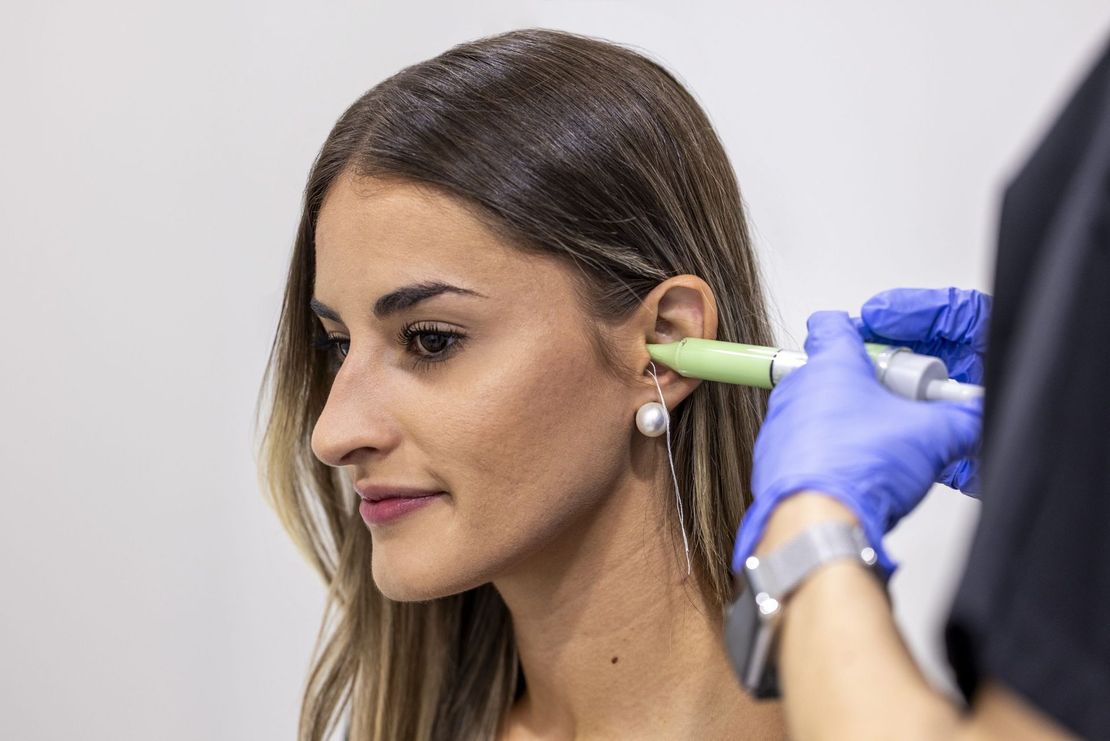 Una mujer se hace perforar las orejas por un médico.